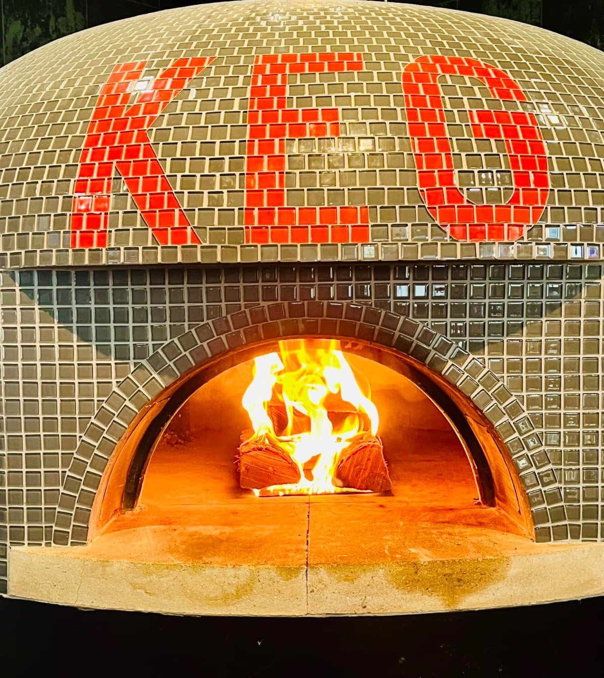 The Keg's tiled wood-fired oven with KEG spelled in red tile and a live fire burning inside