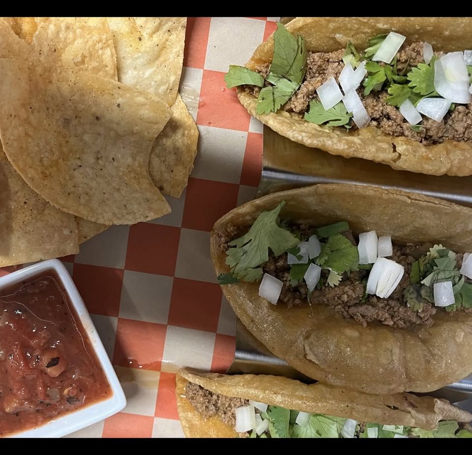 Street tacos topped with cilantro and onion, with chips and salsa